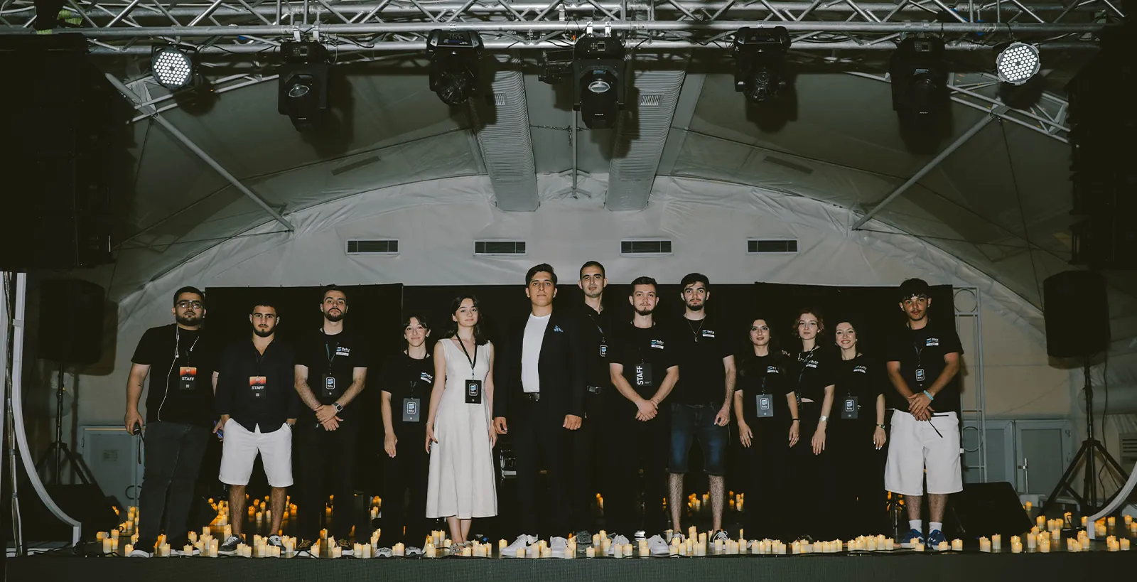 The Candlelight Baku crew standing in a row on stage, the floor around their feet covered in candles